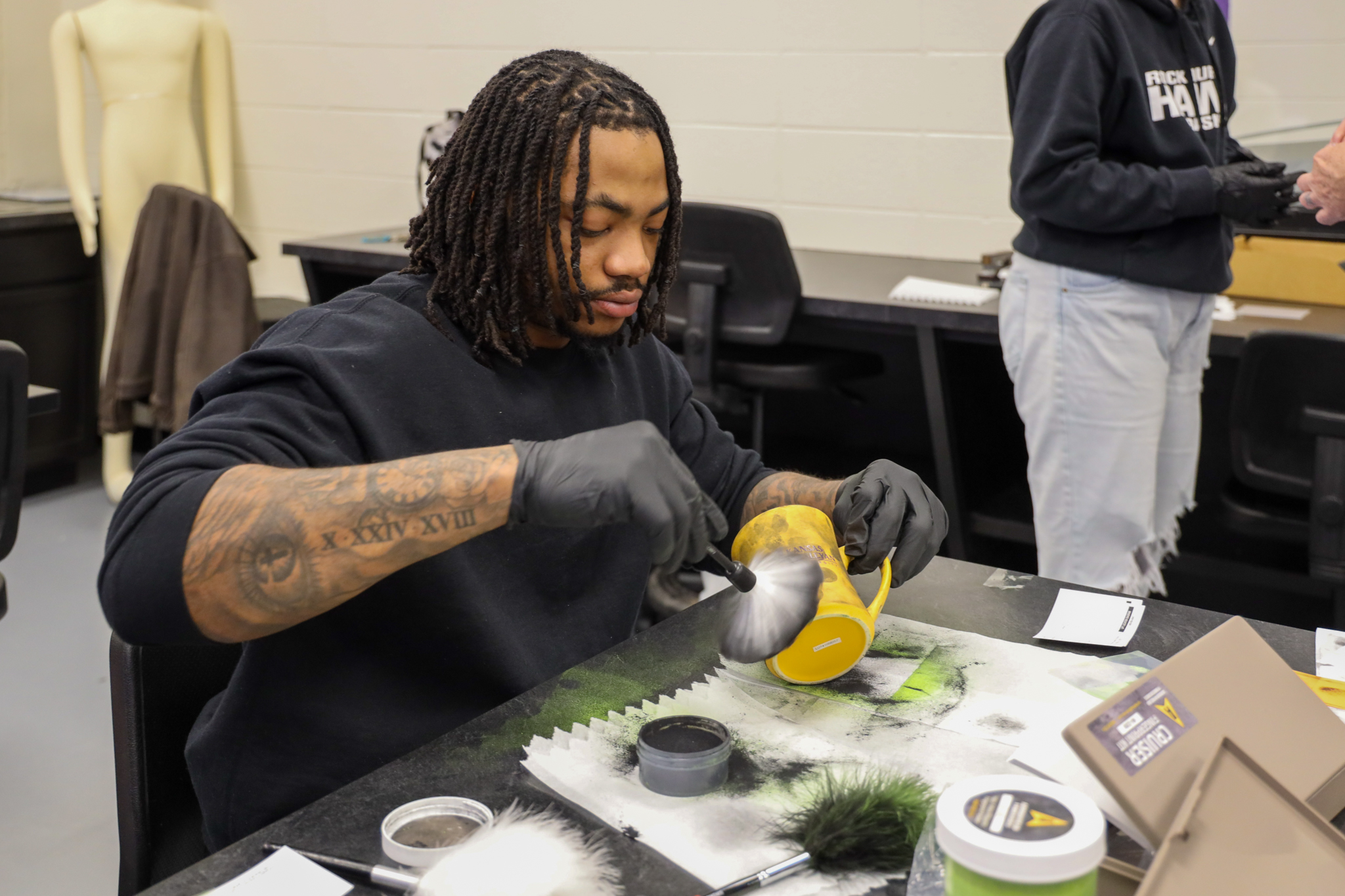 Student dusts mug for fingerprints