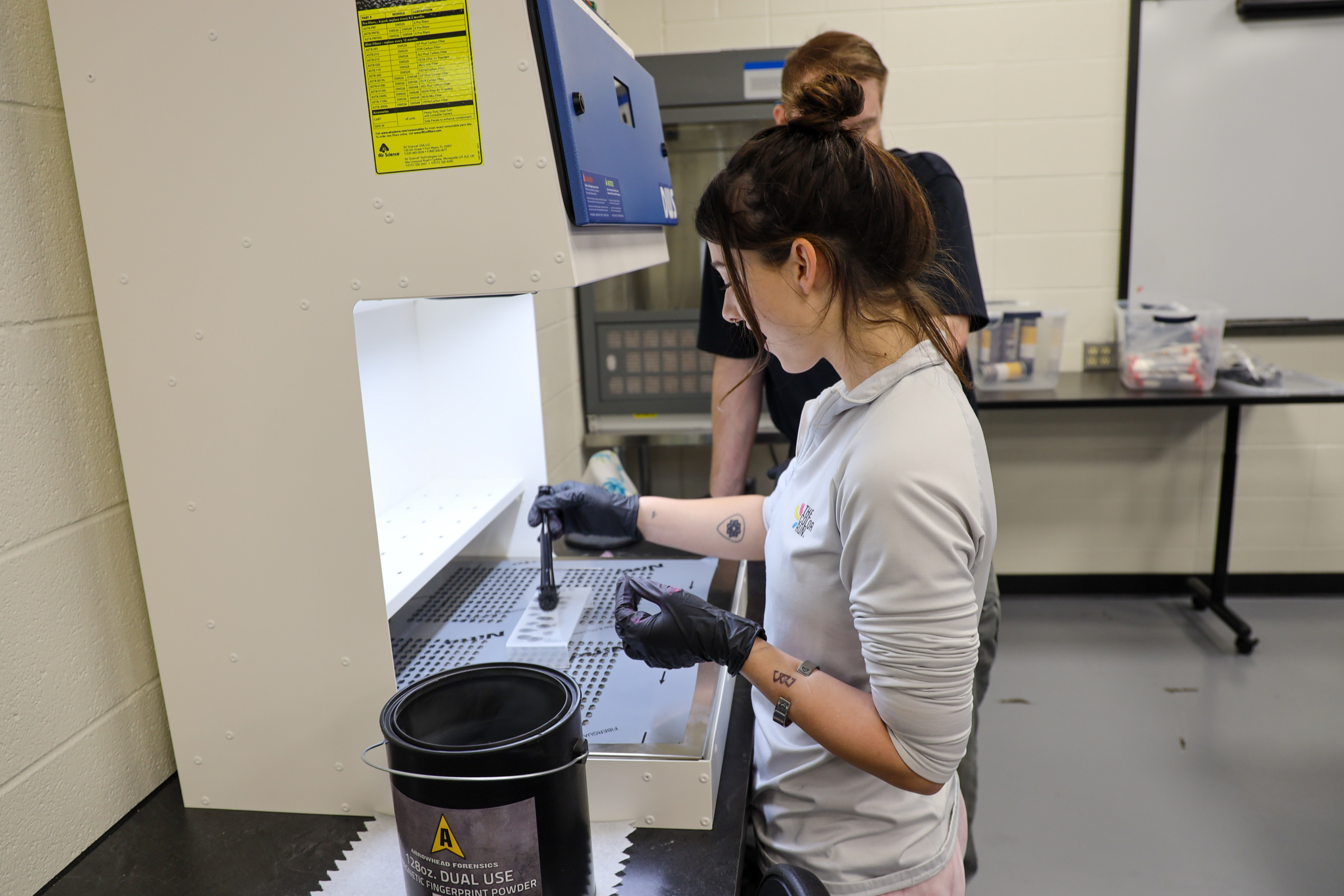 Student using tools to dust for fingerprints