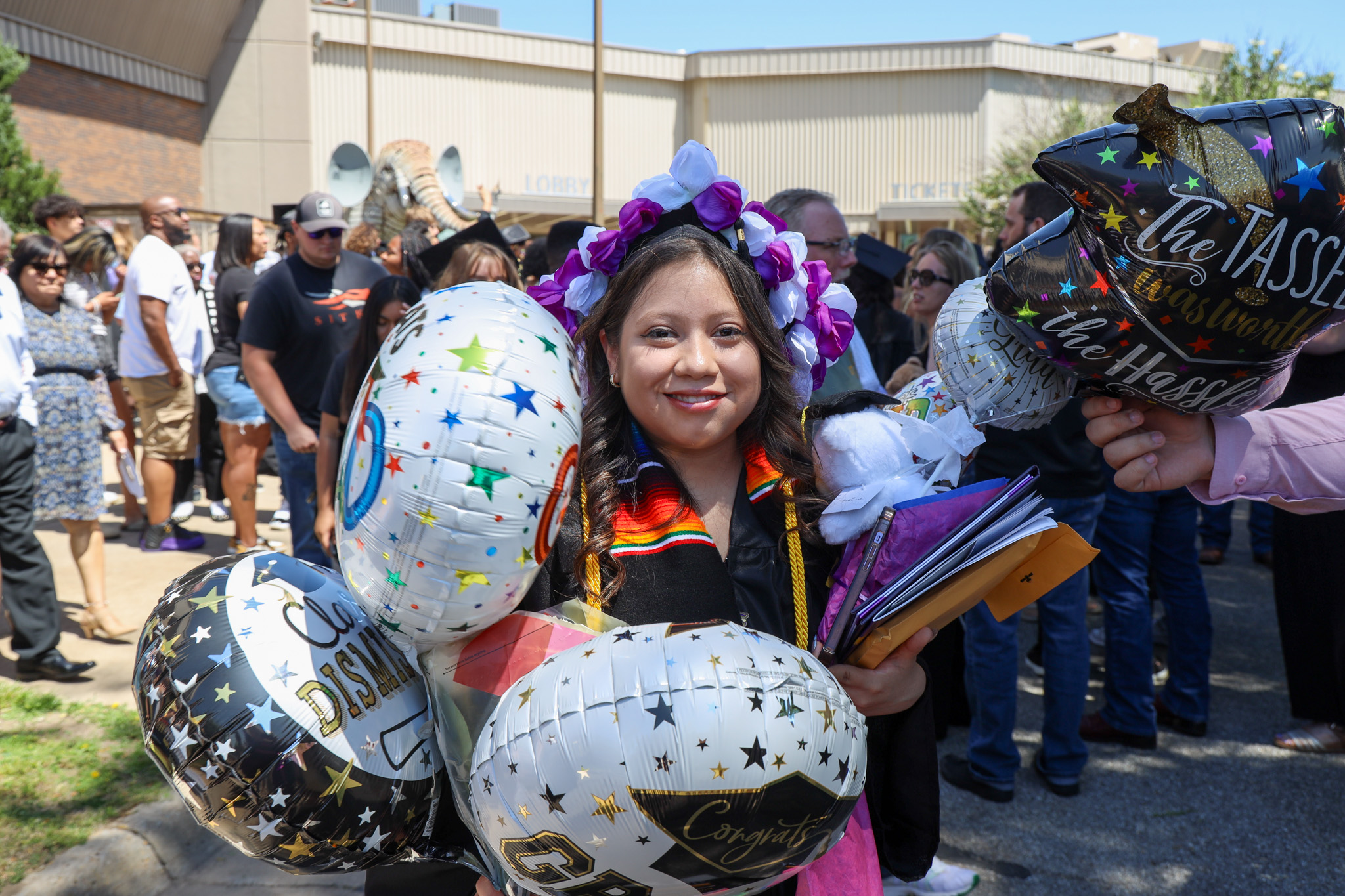 Student at commencement with various balloons and such