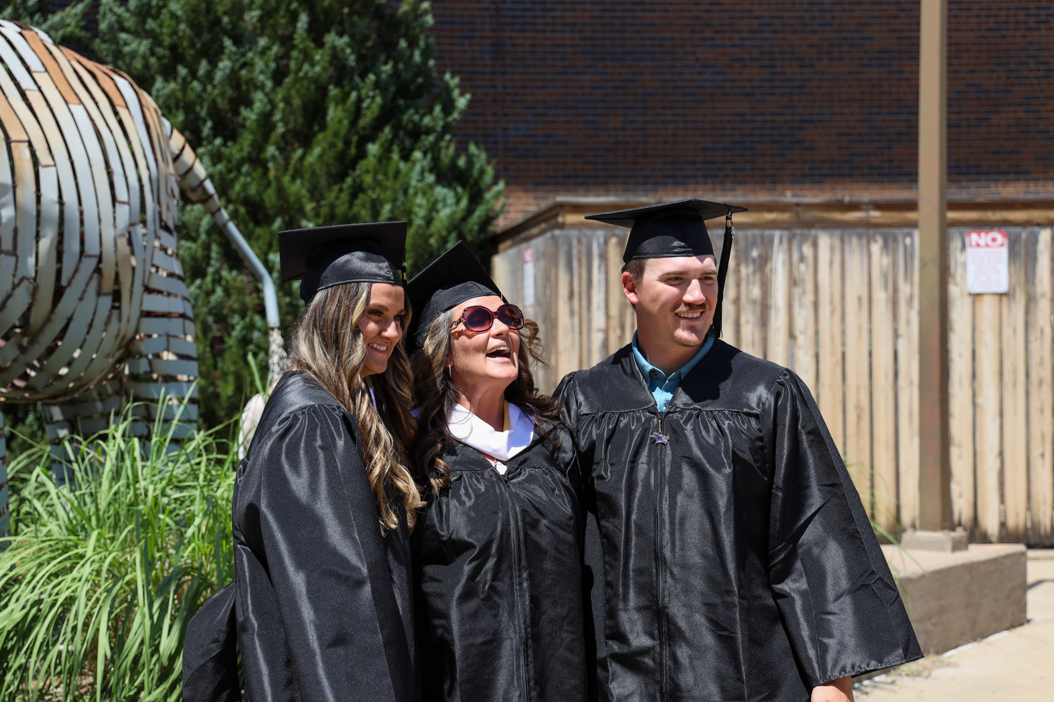 Faculty member with pair of students at commencement