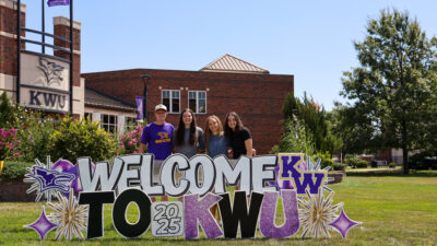 Group of students gathered behind welcome sign