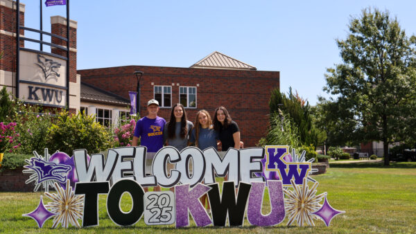 Group of students gathered behind welcome sign