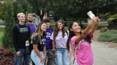 Group of students taking selfie near Coyote statue