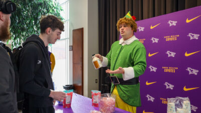 Man in elf costume talking to students