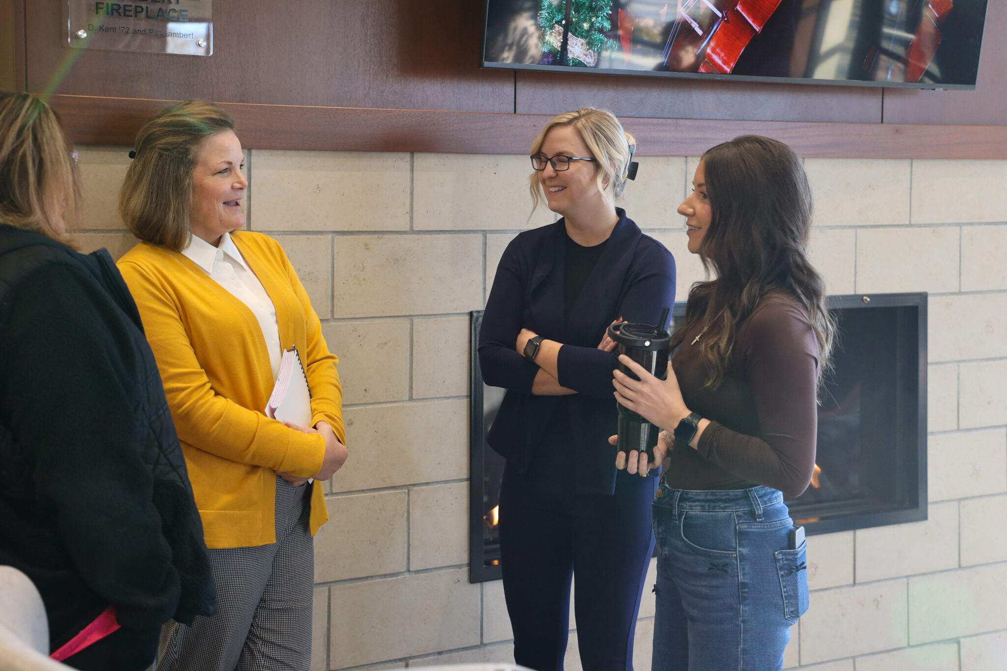 Individuals in front of fireplace talking