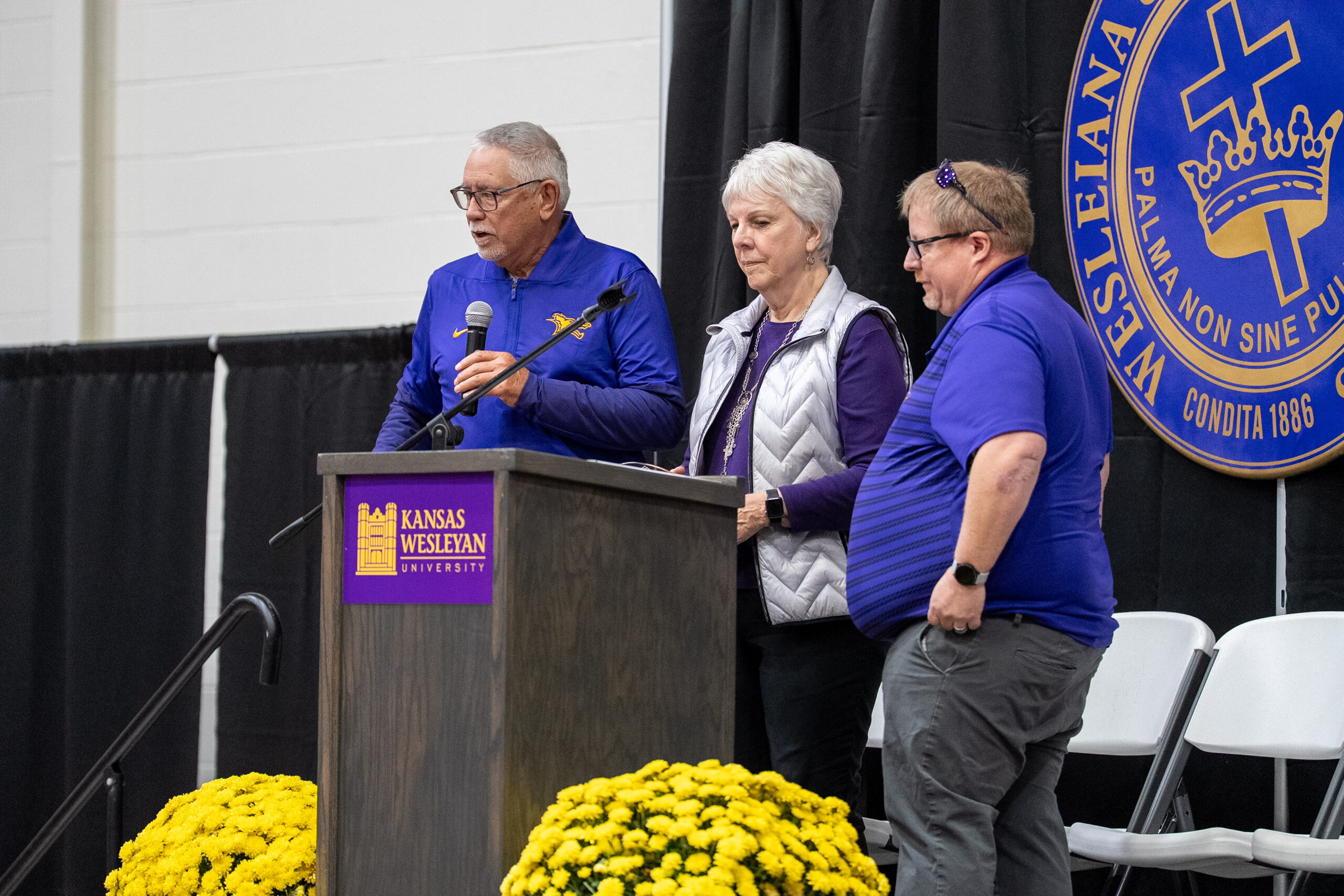 Two men and a woman standing at podium speaking