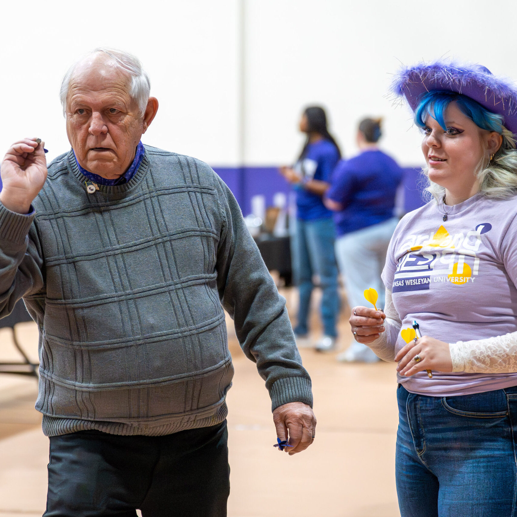 Man playing dart game standing next to woman