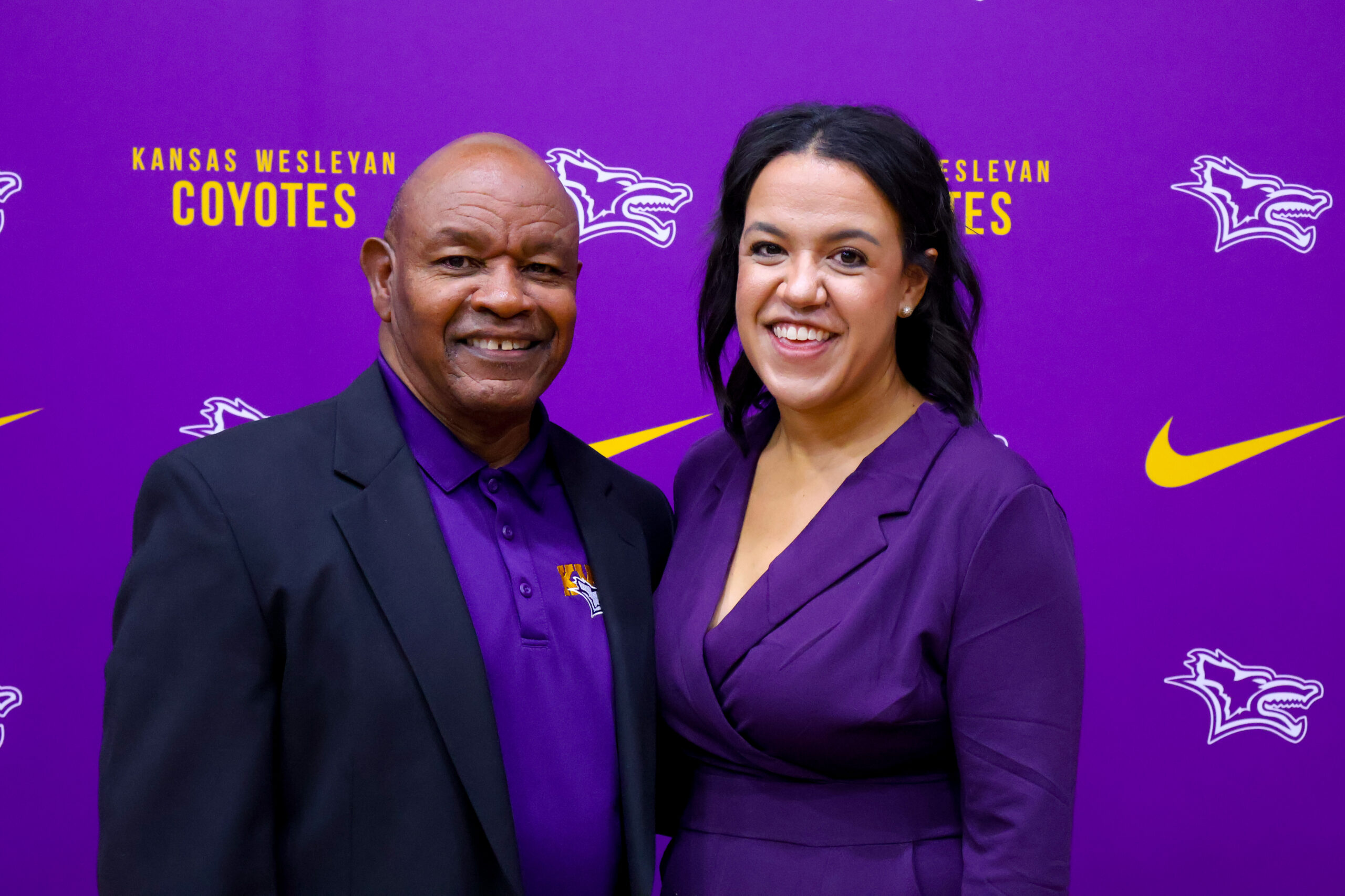 Man and woman in front of each other next to backdrop