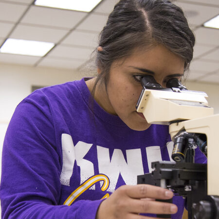 Student looking into microscope in class