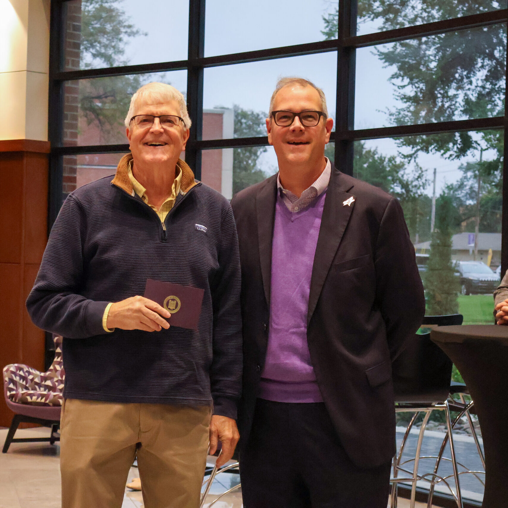 Two men by each other, one with award
