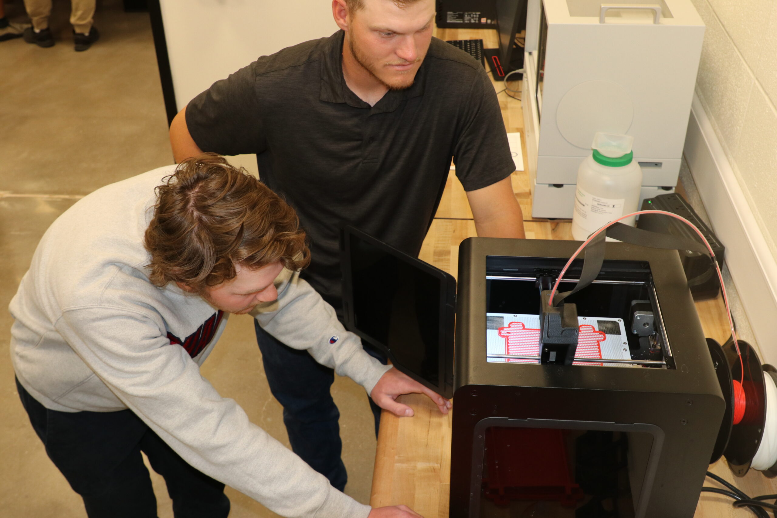 Students operating machine in physics lab.