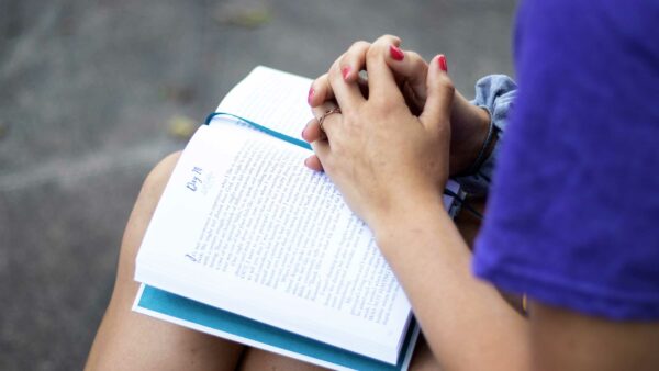 Student sitting with book outside