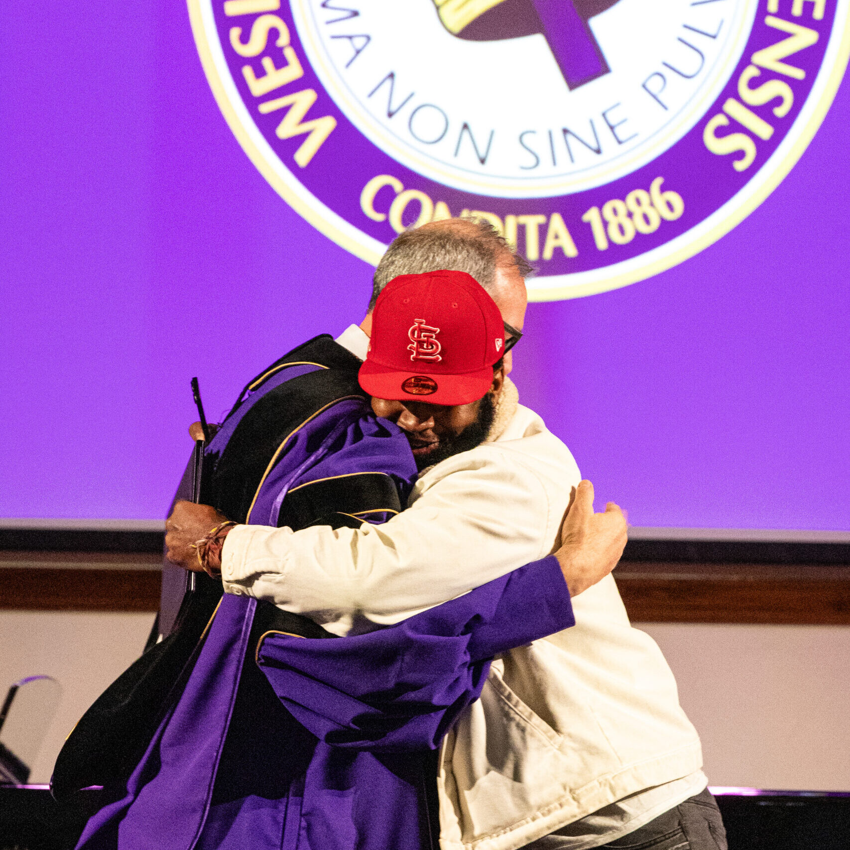 Male graduate hugging president