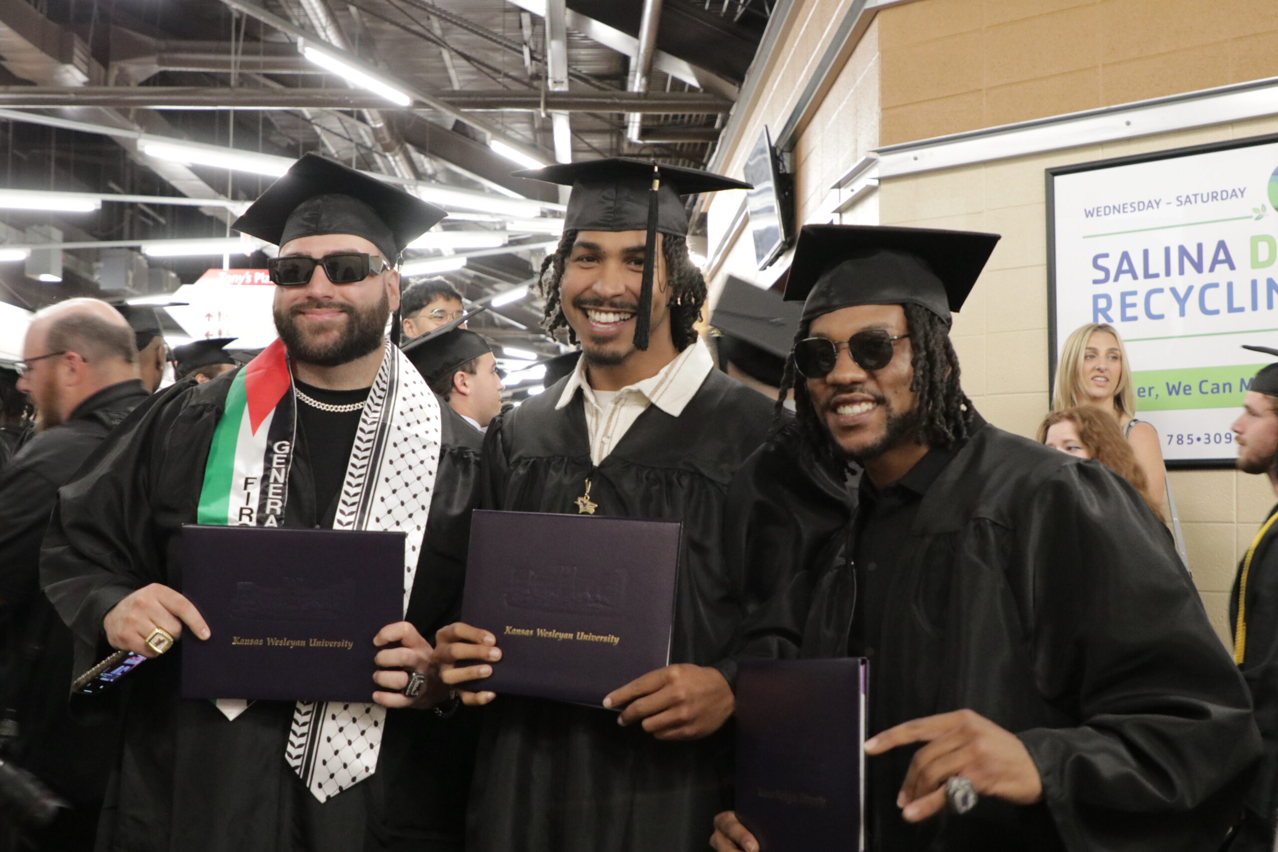 Three graduates hold up diplomas