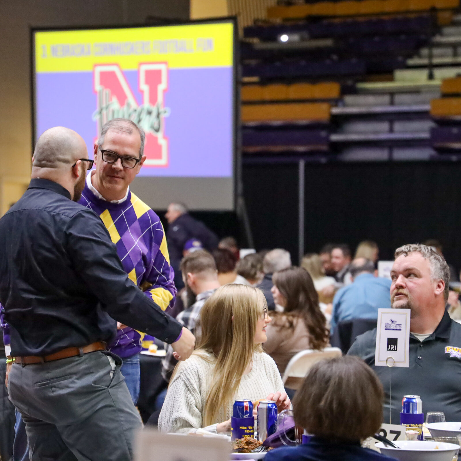 Man talking to other man standing at table