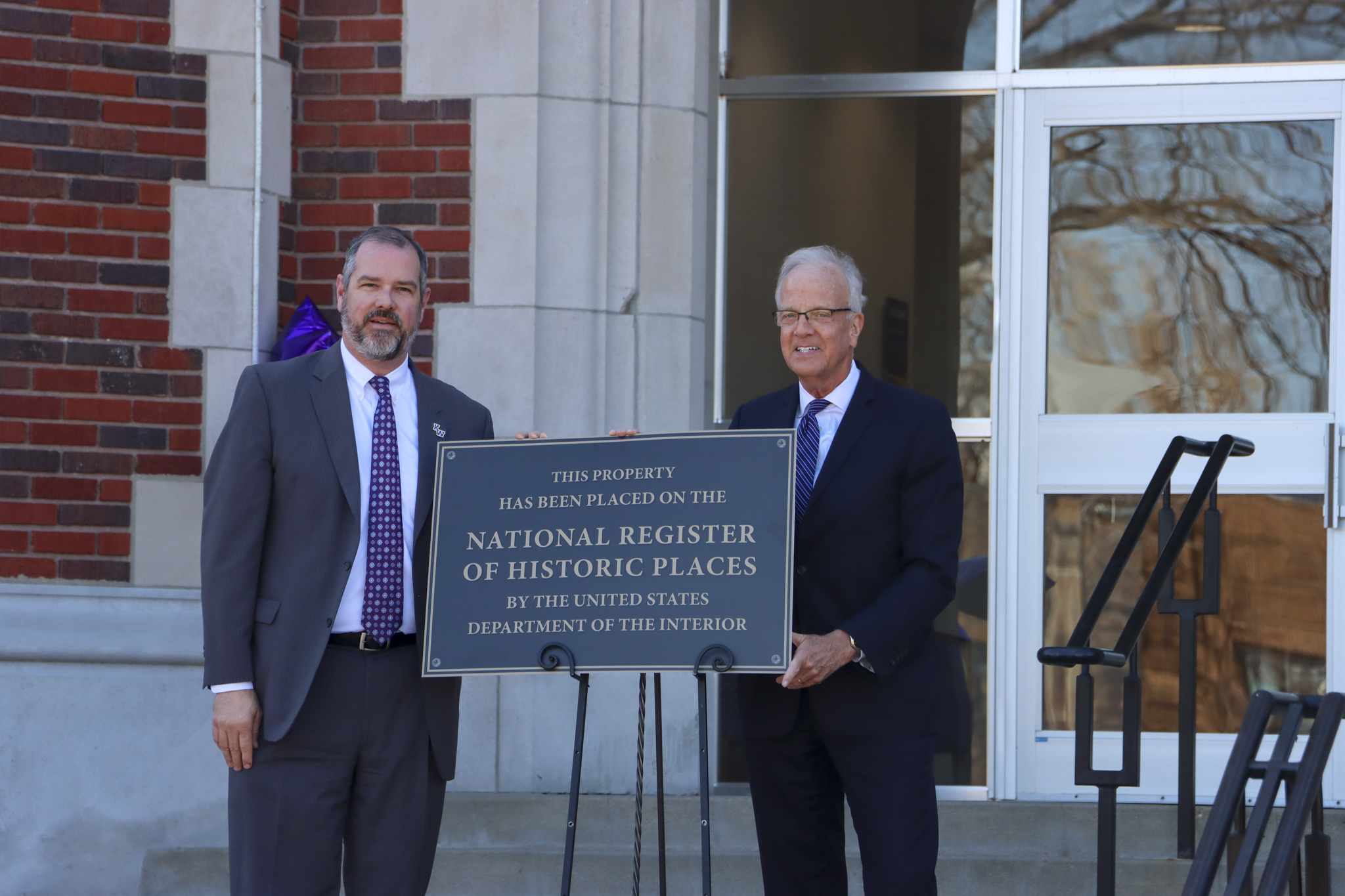 Two men in suits unveiling sign