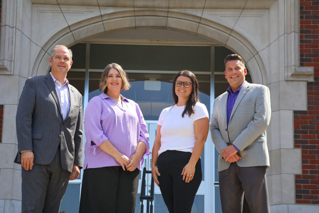 Two men and two women in front of campus building