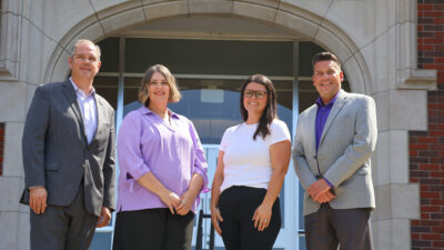 Two men and two women in front of campus building
