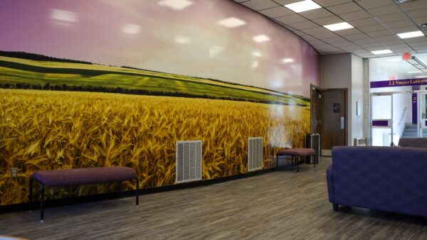 a room with a wall mural of wheat field inside Vanier Lobby