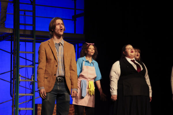 Students singing on stage in musical