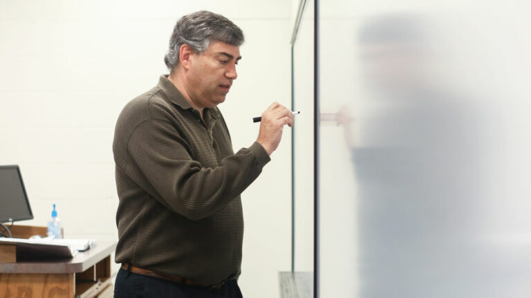 Faculty member writing something on board